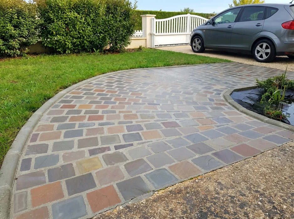 Allée de jardin extérieure pavée en dalles de schiste multicolores (tons rouges, gris, ocres), posées en opus incertum avec joints serrés au mortier