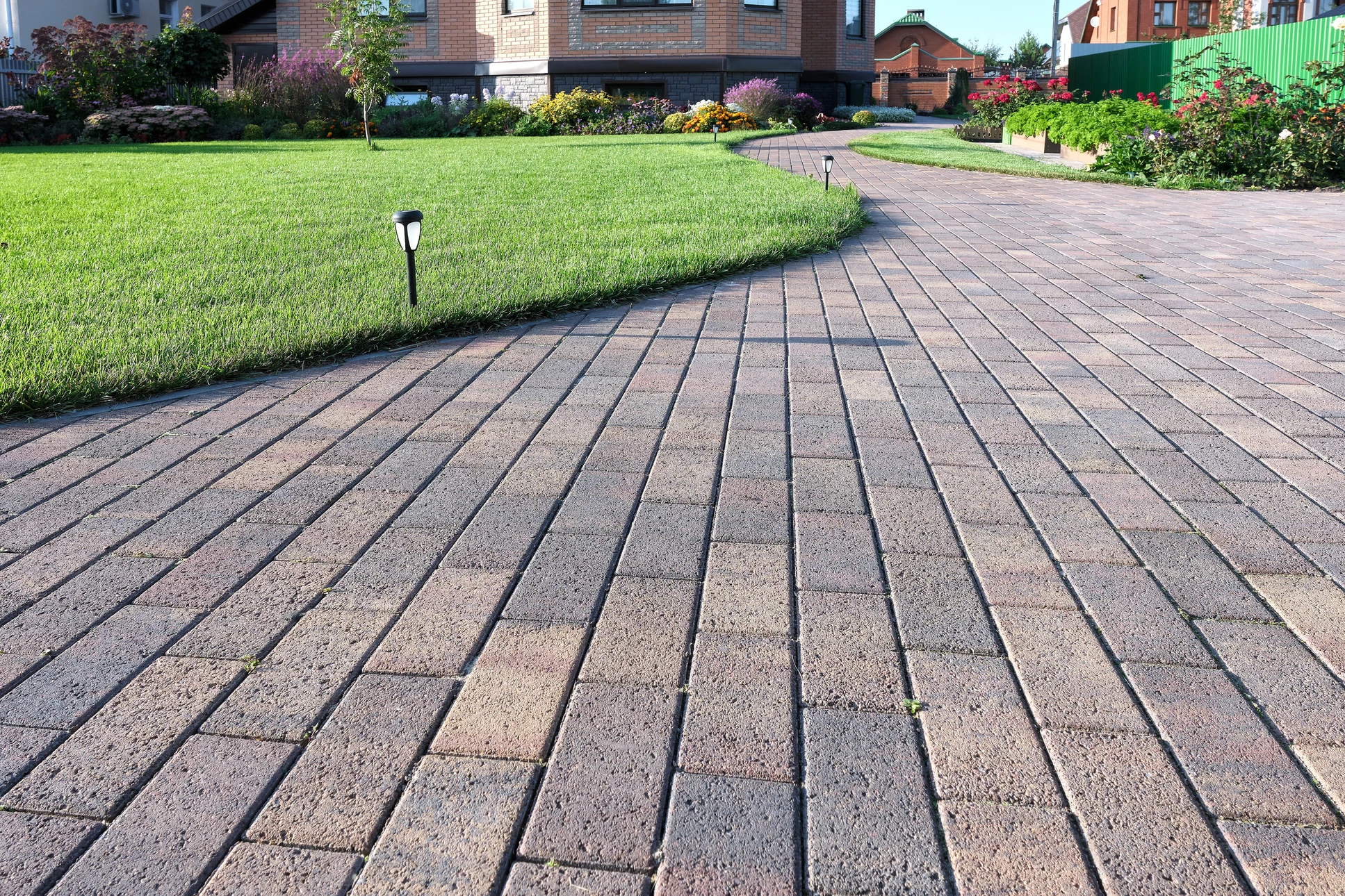 Aménagement paysager extérieur résidentiel avec terrasse en pavés autobloquants beiges disposés en opus romain