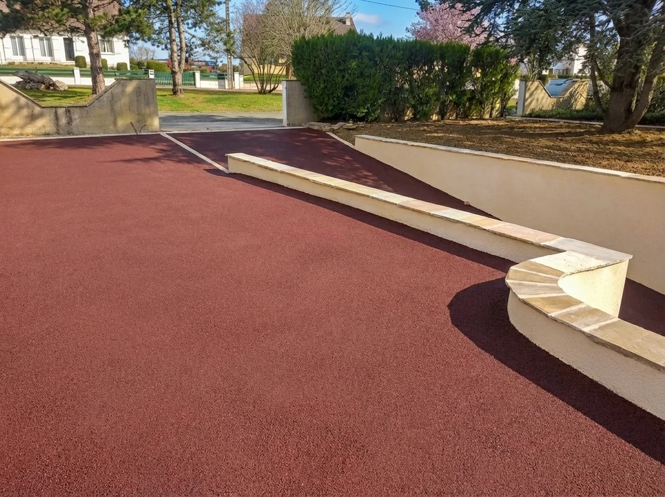 Allée de parking extérieure rénovée avec revêtement en béton désactivé beige-gris, délimitée par des joints de fractionnement en béton lissé formant des rectangles